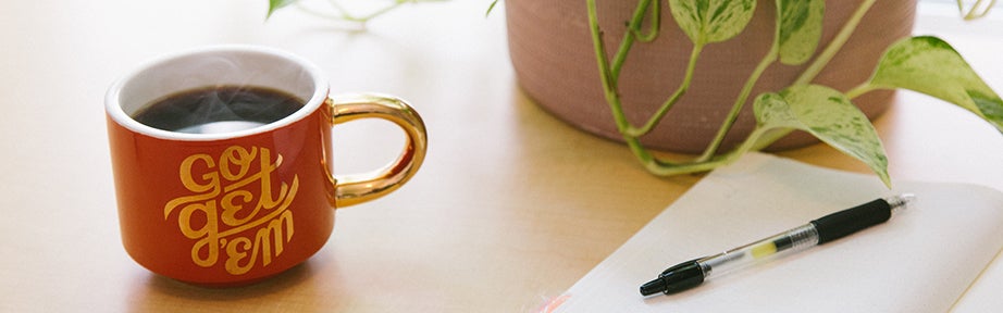 Cup on desk with pen and paper